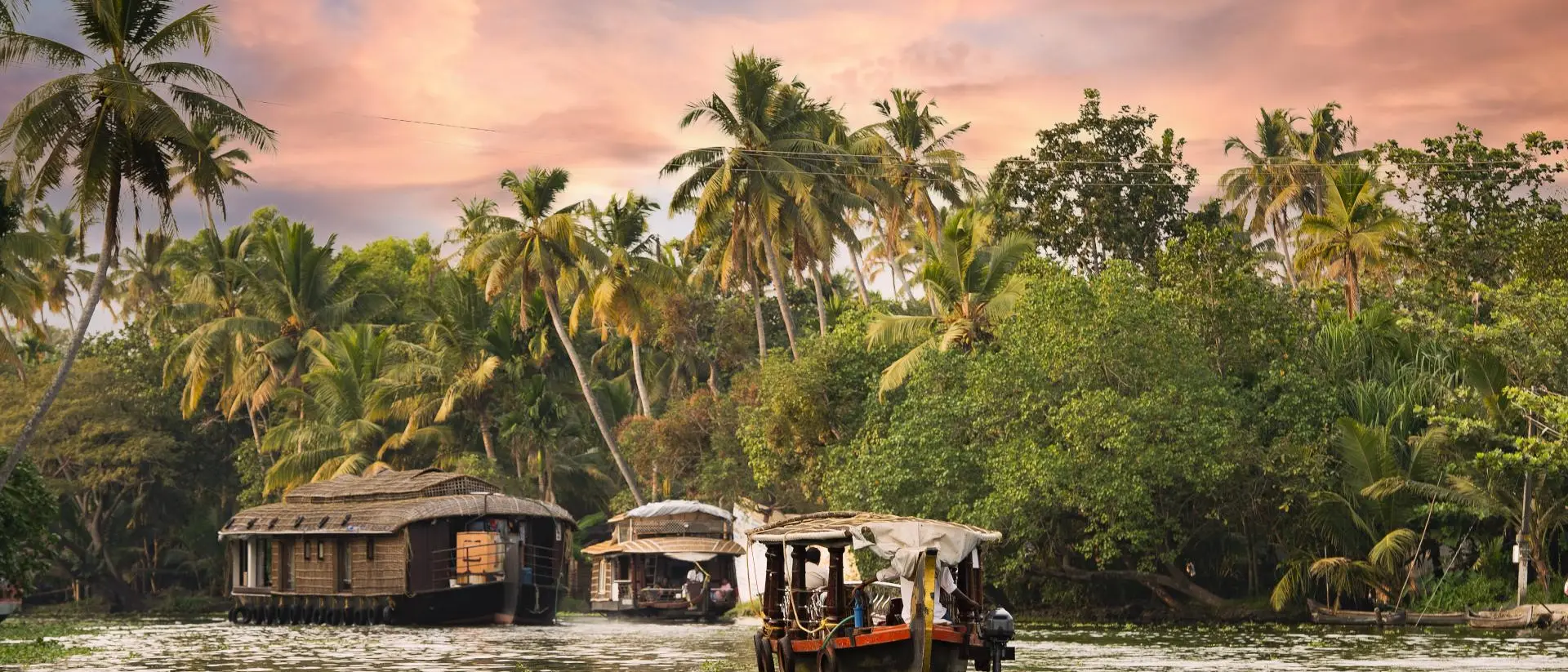Stunning view of a house boat sailing on the Alleppey's backwaters during a beautiful sunset