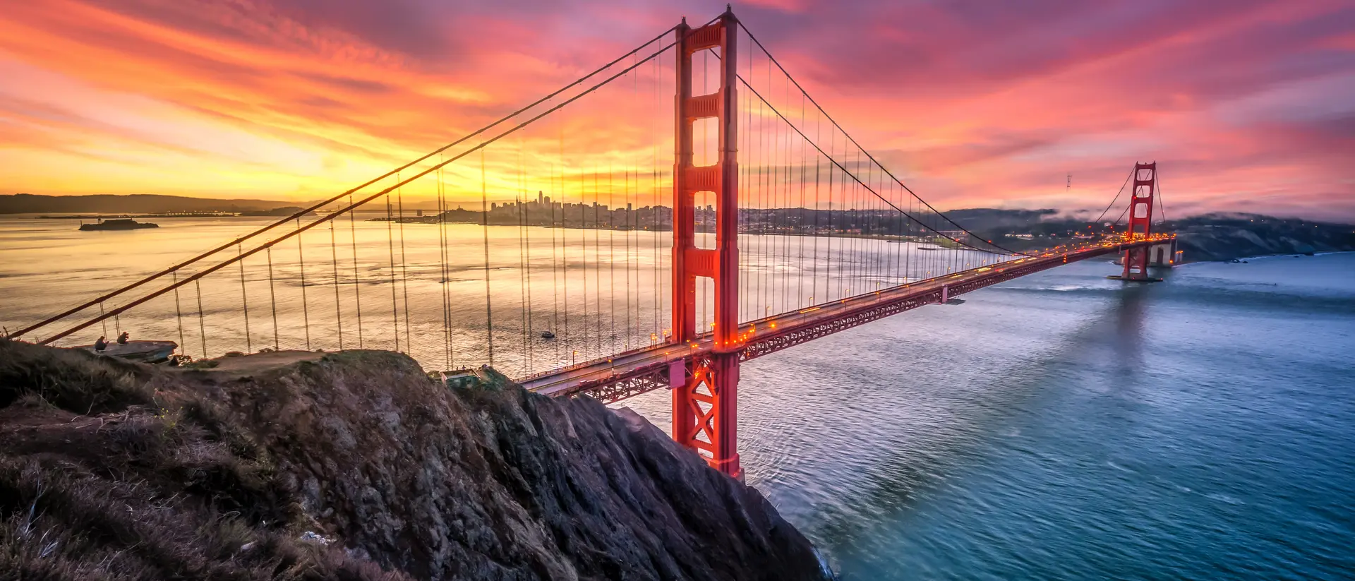 Colored sunrise with wide shot of bridge and city in the background