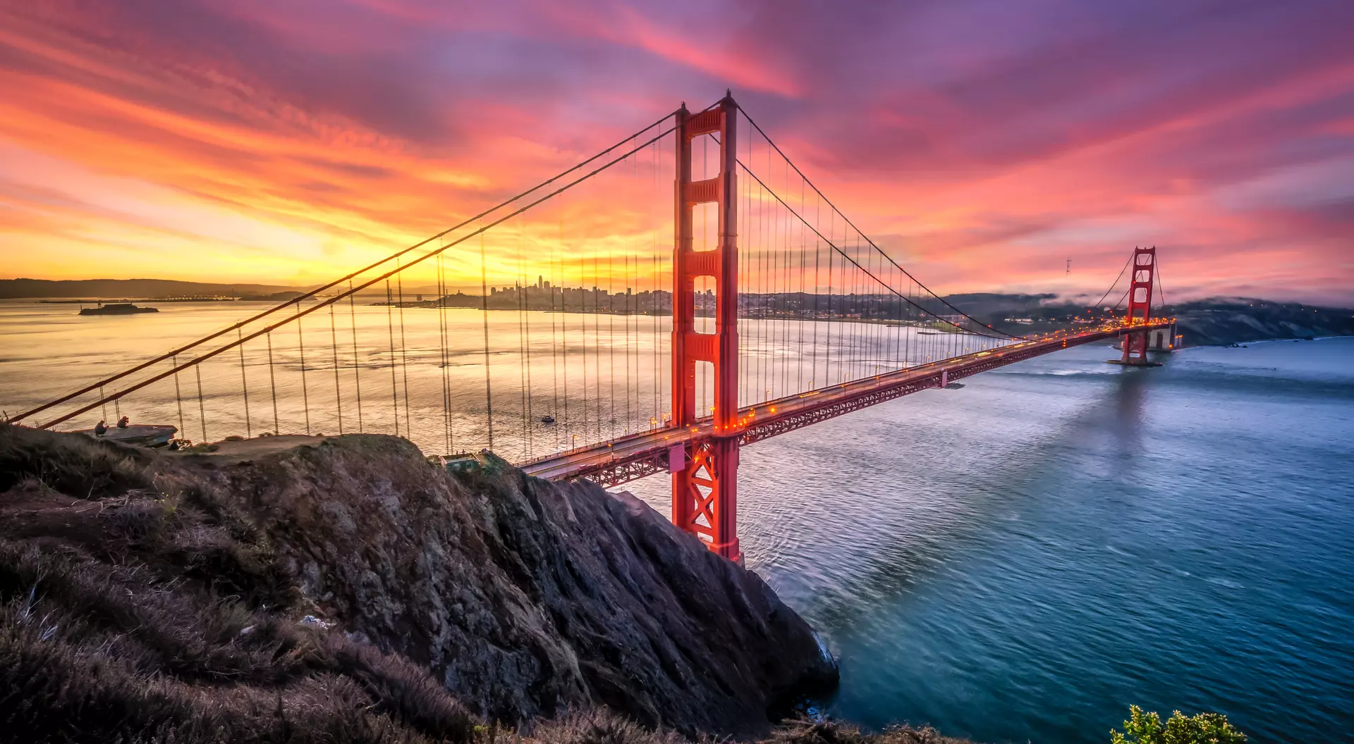 Golden Gate Bridge, San Francisco, United States Colored sunrise with wide shot of bridge and city in the background