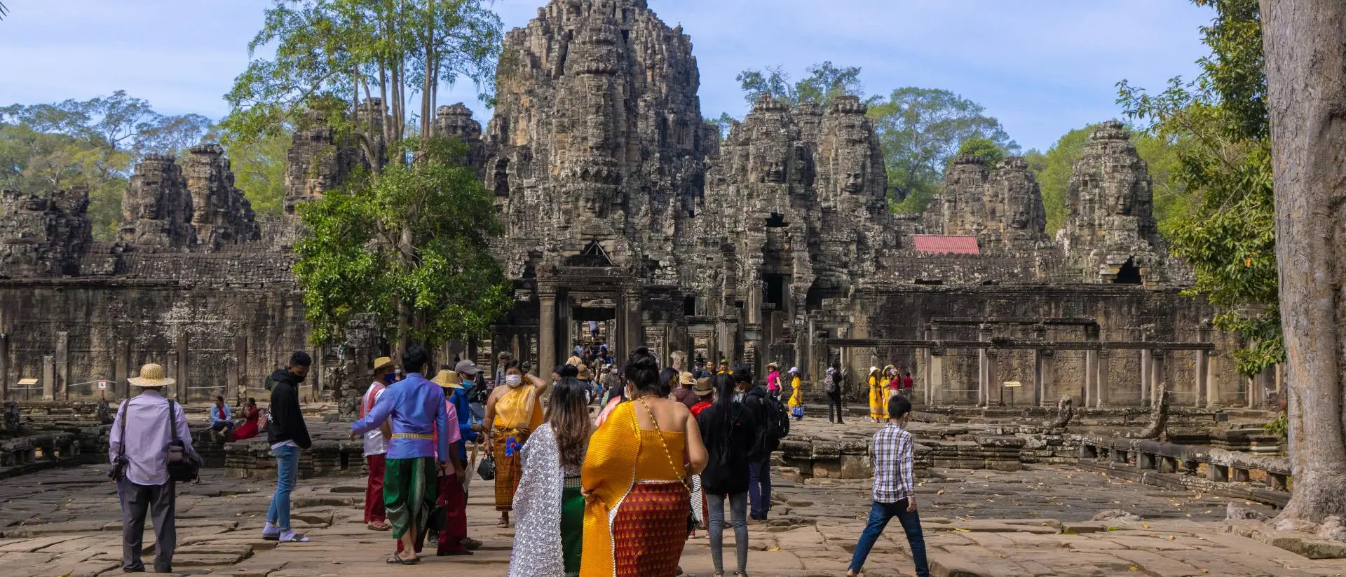 Visitors explore ancient stone ruins surrounded by lush greenery on a sunny day.