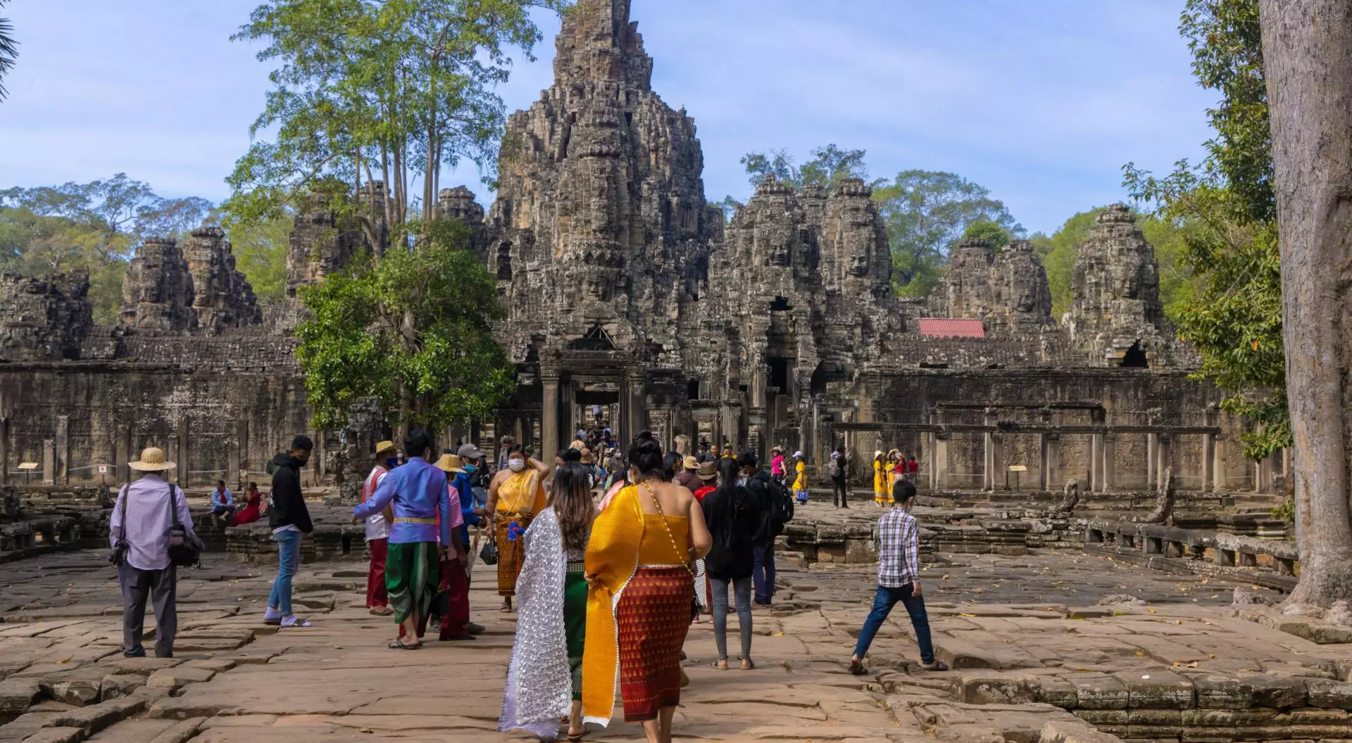 Visitors explore ancient stone ruins surrounded by lush greenery on a sunny day.