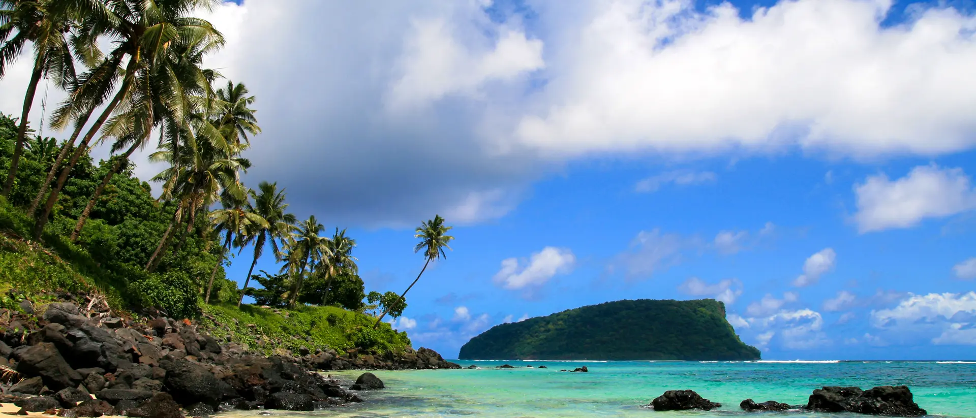 Tropical seascpape, golden sandy beach with palm trees and pristine blue waters of Pacific Ocean, view from Upolu to Nu'utele Island