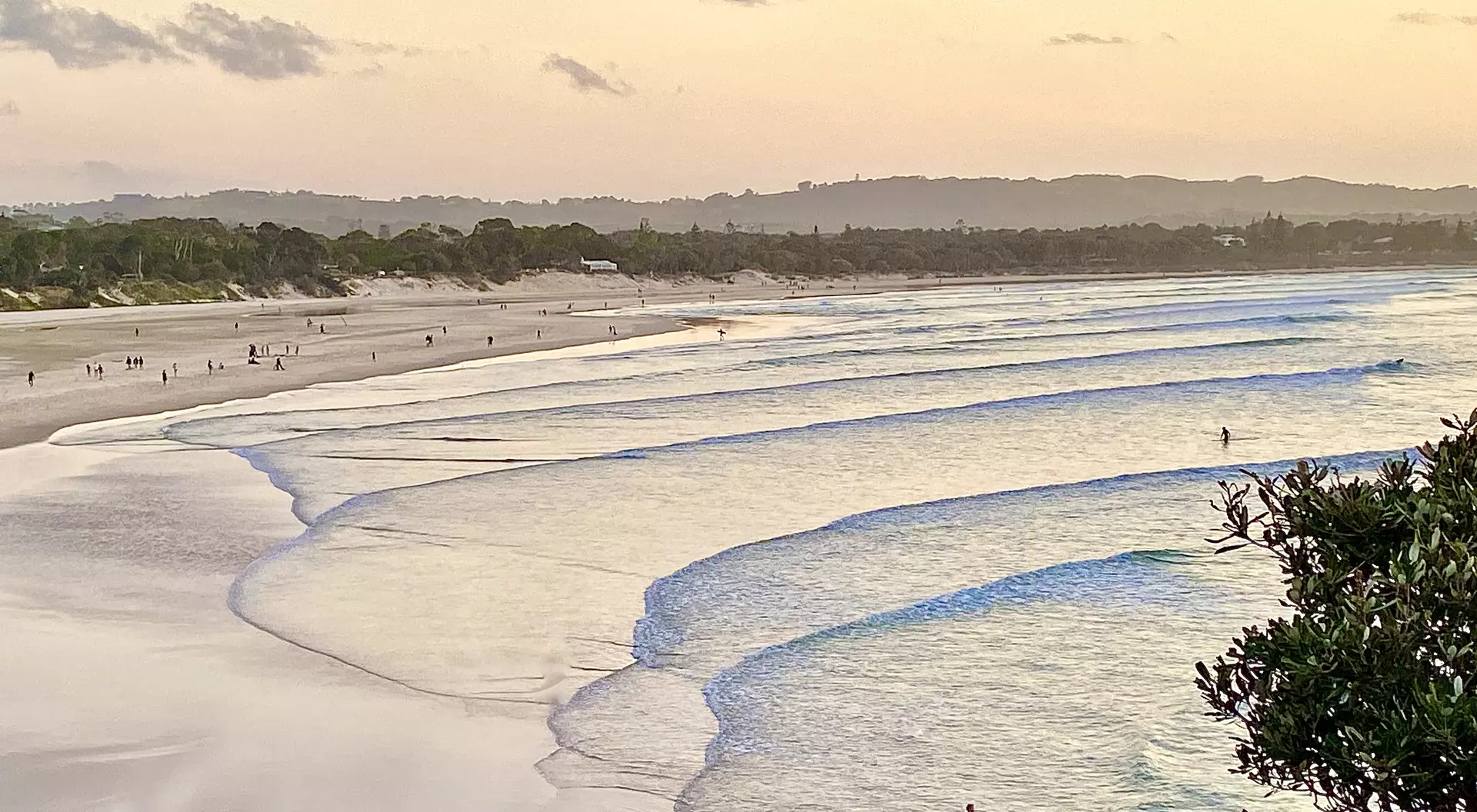 View of sunset seascape and shoreline after surfing calm breaking waves under a pastel color sky at Byron Bay NSW Australia