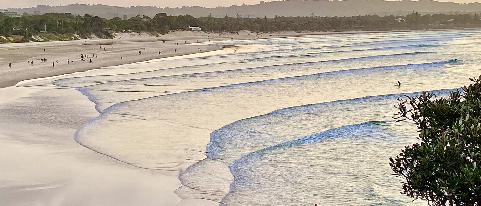 View of sunset seascape and shoreline after surfing calm breaking waves under a pastel color sky at Byron Bay NSW Australia