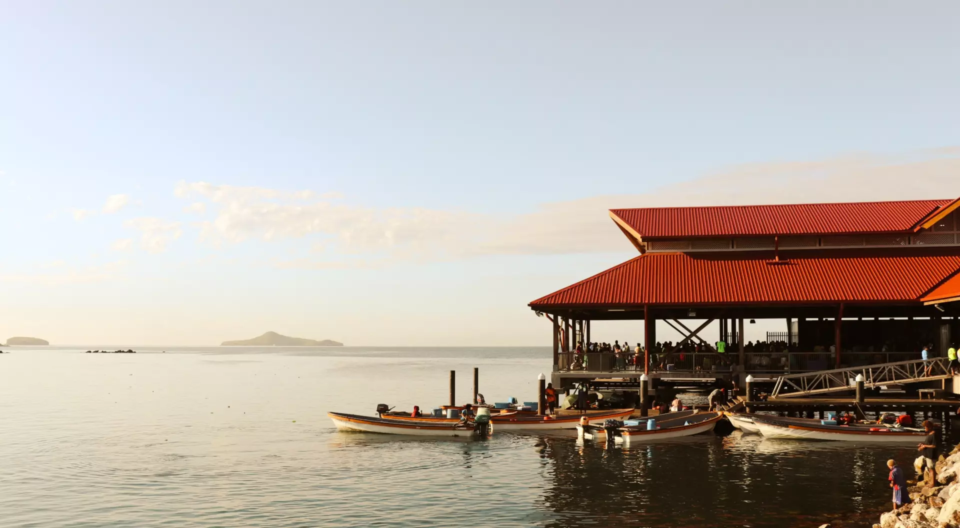 Boats on dock beside oceanside Papua New Guinea market