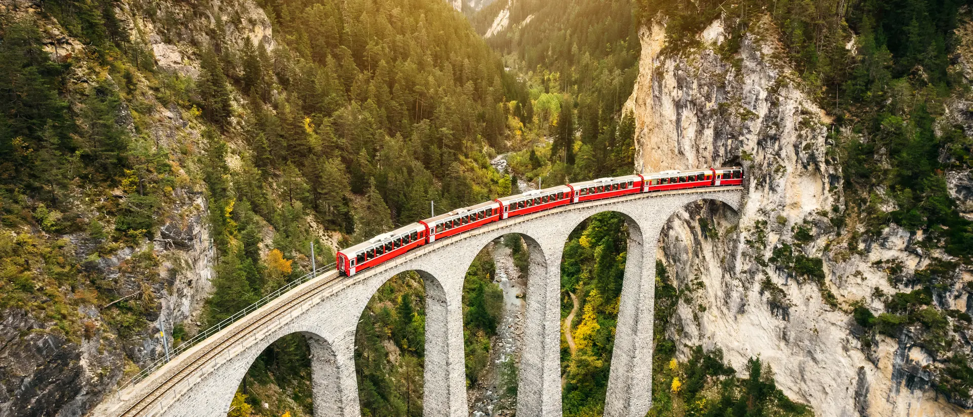 Unravel the beauty of Switzerland on captivating rail journeys. Train crossing Landwasser Viaduct on raethian railway in Filisur – Albula, Graubunden, Switzerland
