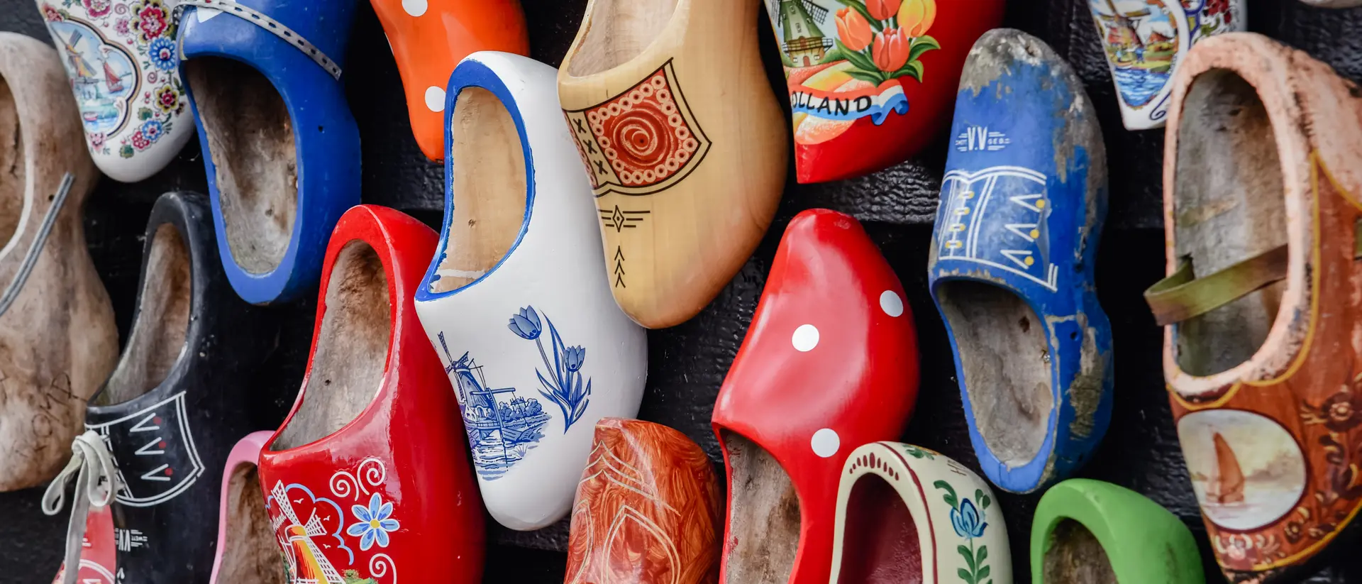 Colorful decorative wooden shoes arranged on a wall, showcasing various patterns and designs.