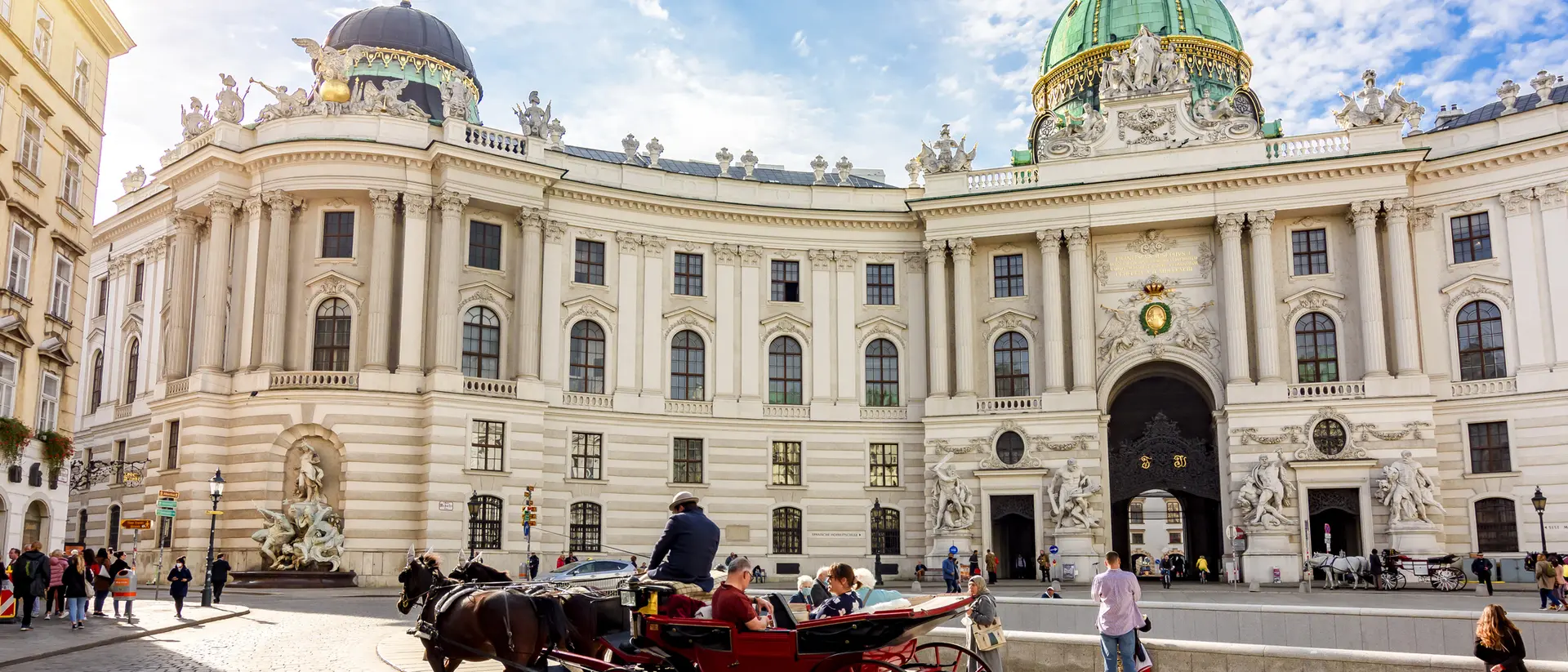 Horse-drawn carriage in front of a grand, historic building with a green dome under a blue sky.