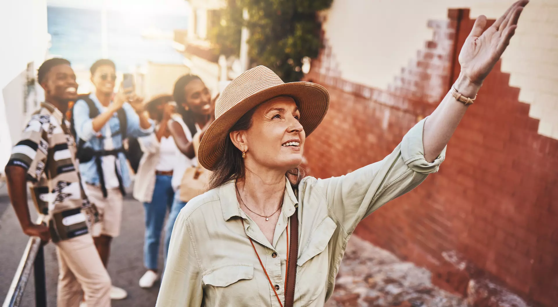 Woman, city guide and group of happy tourists, pointing at local architecture