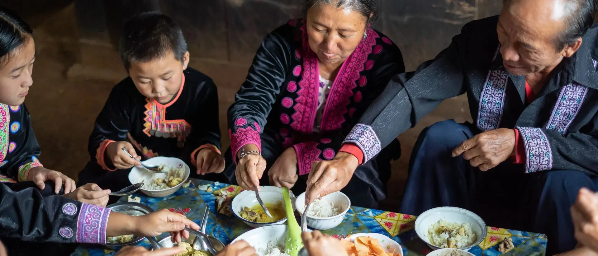A family sits together sharing a meal, enjoying traditional dishes in a warm, cozy setting.
