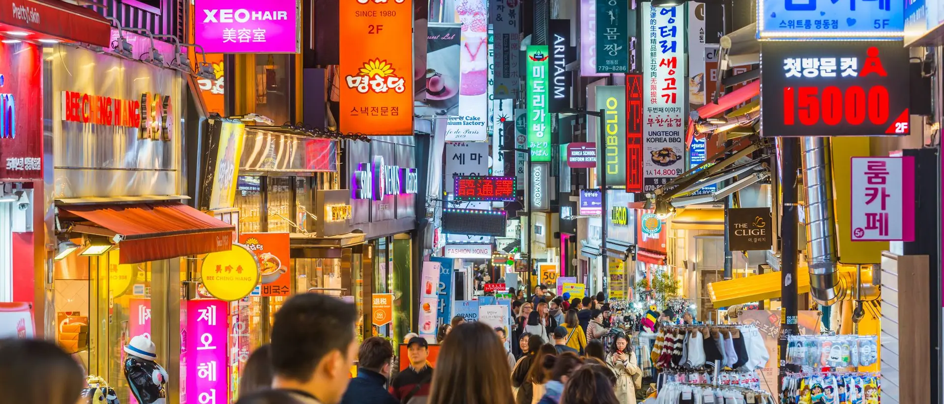 Busy street in South Korea filled with colorful signs, shops, and a crowd of people exploring.
