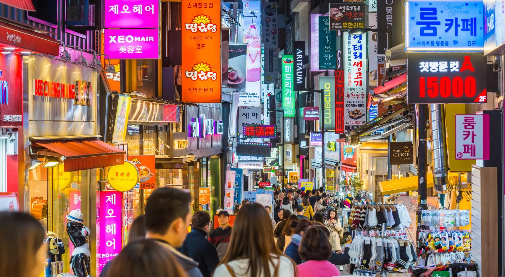 Busy street in South Korea filled with colorful signs, shops, and a crowd of people exploring.