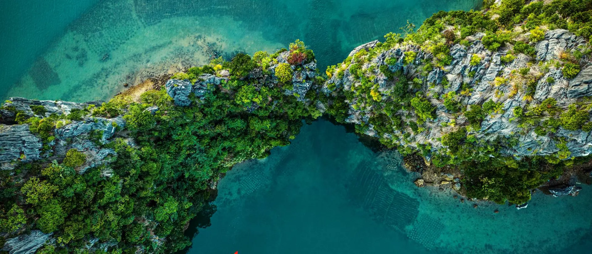 Drone view on rocks and canoes floating on turquoise water in the Halong Bay,