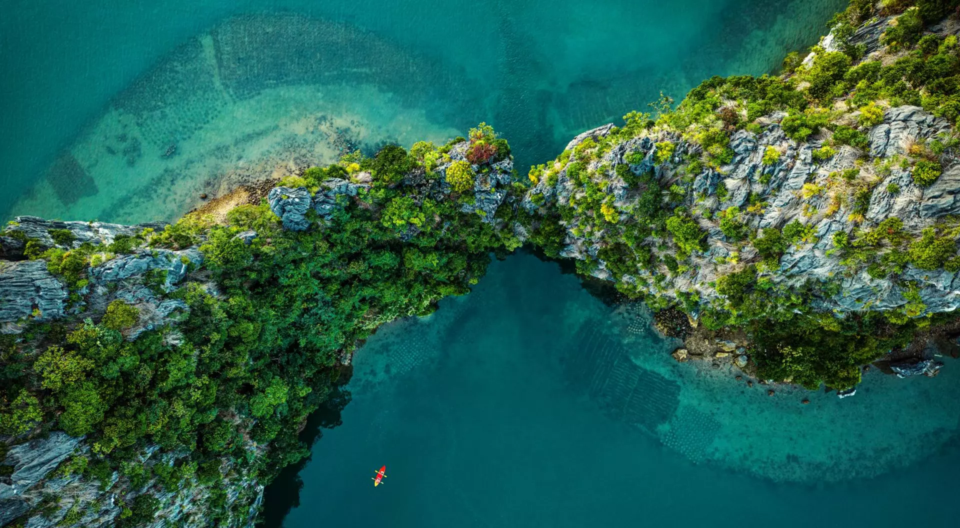 Drone view on rocks and canoes floating on turquoise water in the Halong Bay,