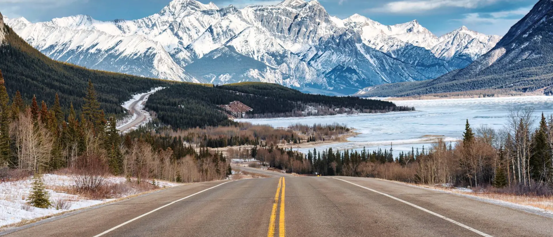 Beautiful scenery of Road trip on highway with rocky mountains and frozen lake