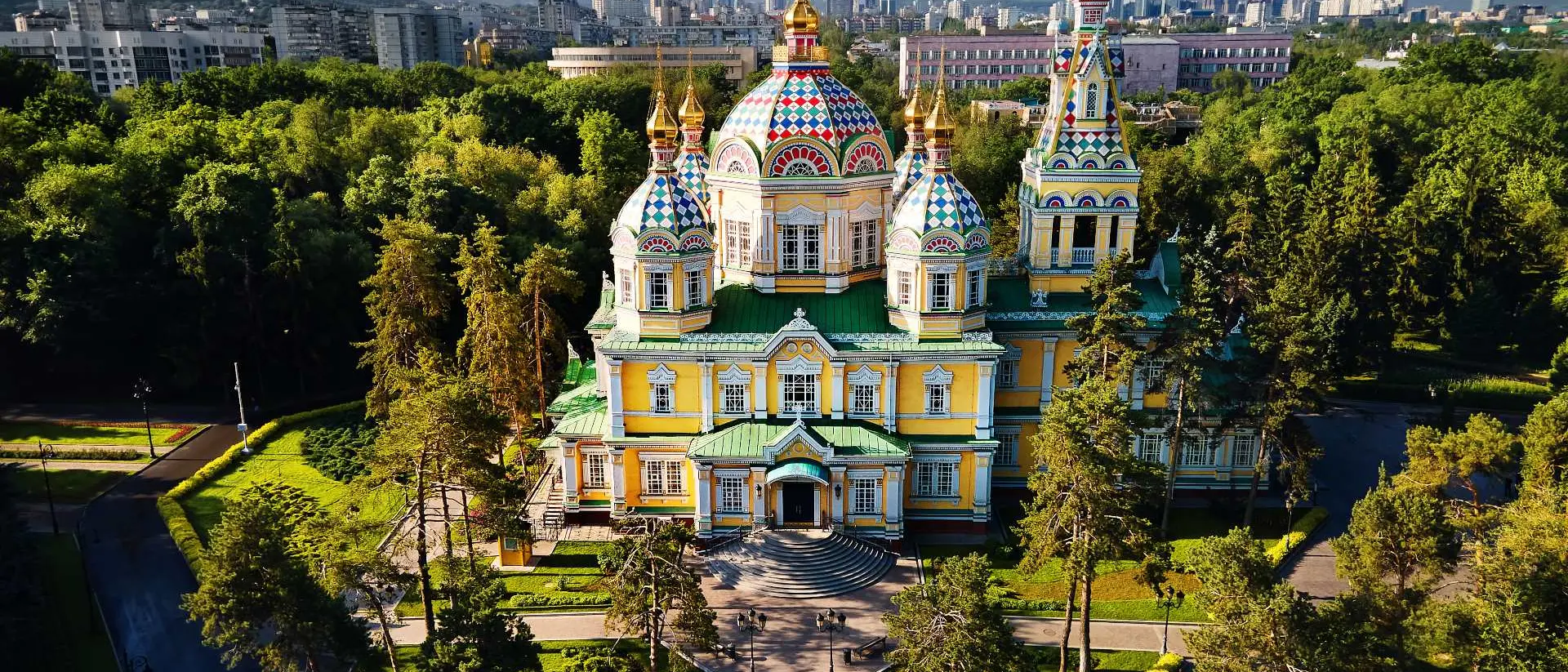 Aerial view of the Zenkov Cathedral in Panfilov Park against blue sky and and snowy mountains in Almaty city, Kazakhstan