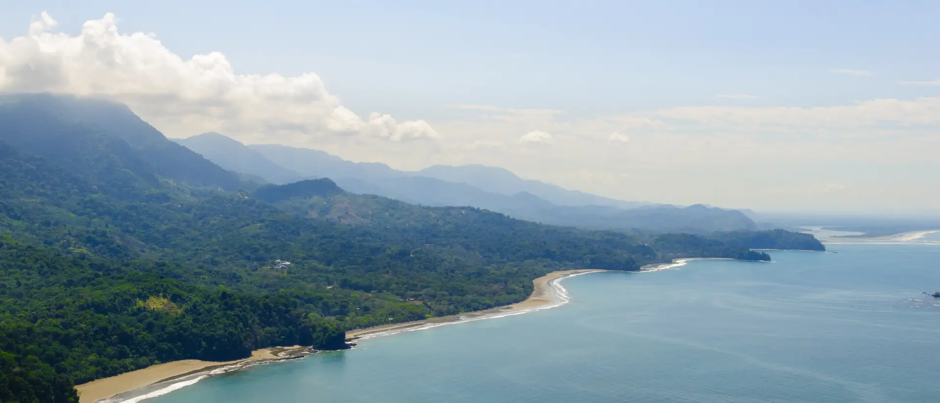 Vibrant tropical forests flow down from the mountains to the sandy beaches along the coast. Aerial view of the Costa Ballena near Dominical, Costa Rica