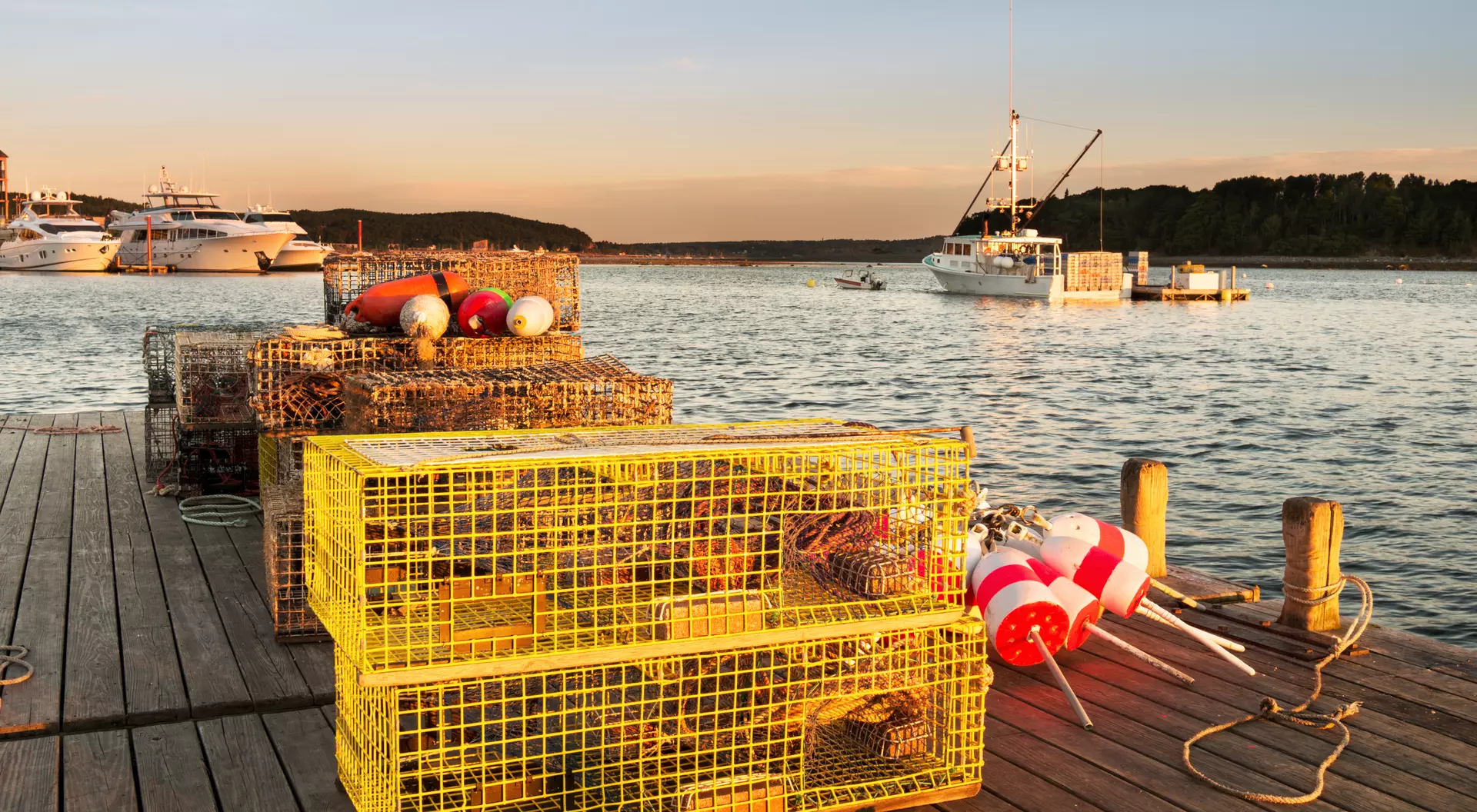 Pier in Maine Harbor with lobster traps in foreground and Lobster boats in background