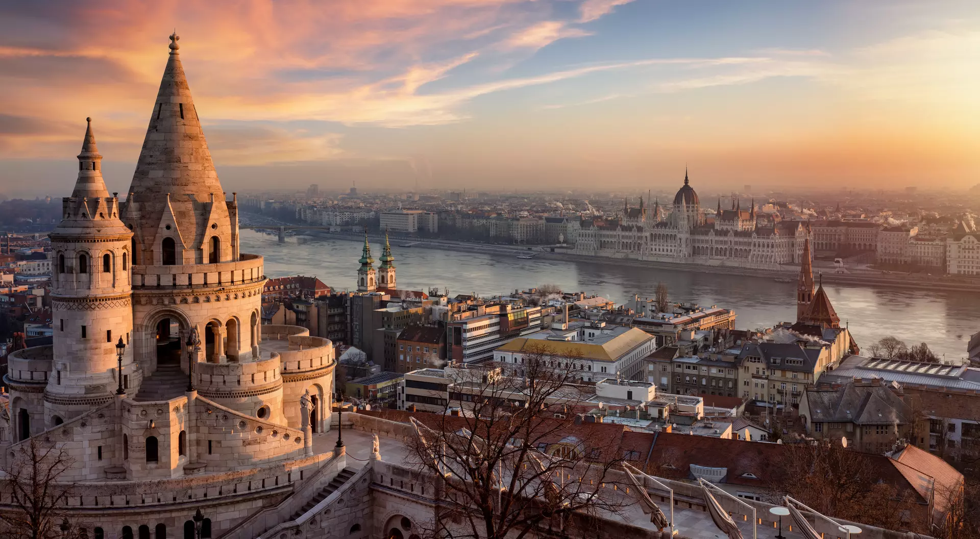Sunset view of Budapest, featuring the Fisherman's Bastion and the Parliament building along the Danube River.