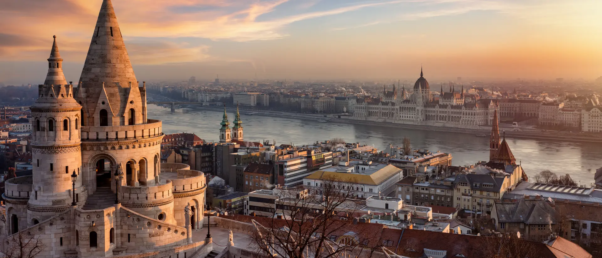 Sunset view of Budapest, featuring the Fisherman's Bastion and the Parliament building along the Danube River.
