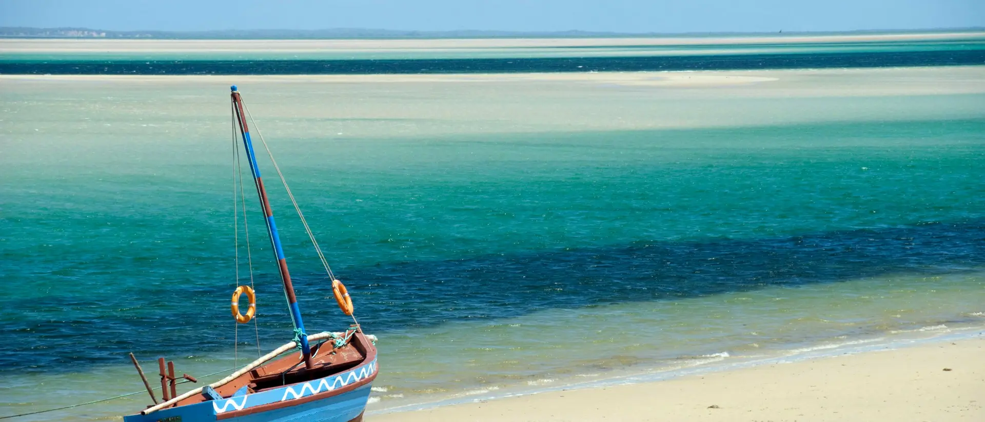 A Dhow (boat) sitting at the water's edge on a beach