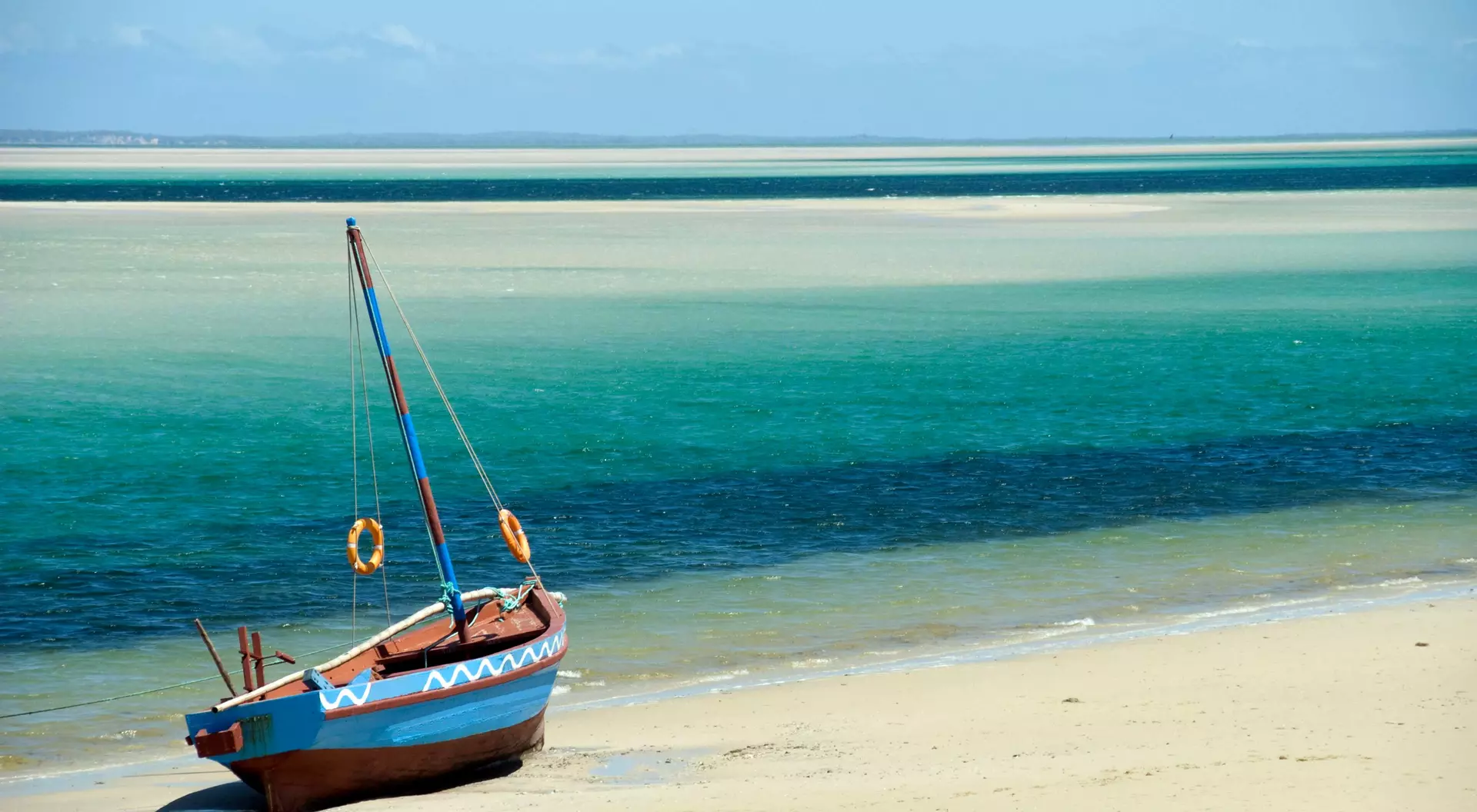 A Dhow (boat) sitting at the water's edge on a beach