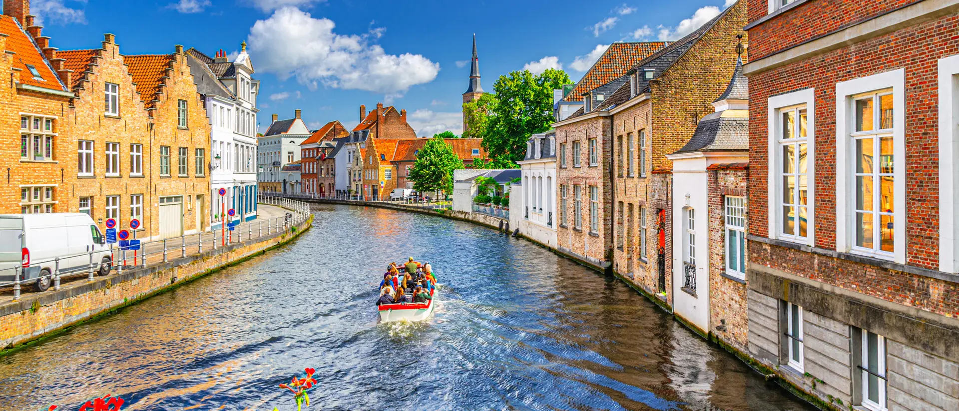 A scenic canal in a charming town, with colorful buildings and a boat carrying passengers gliding along the water.