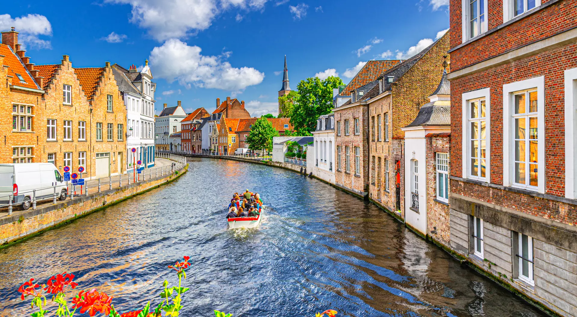 A scenic canal in a charming town, with colorful buildings and a boat carrying passengers gliding along the water.