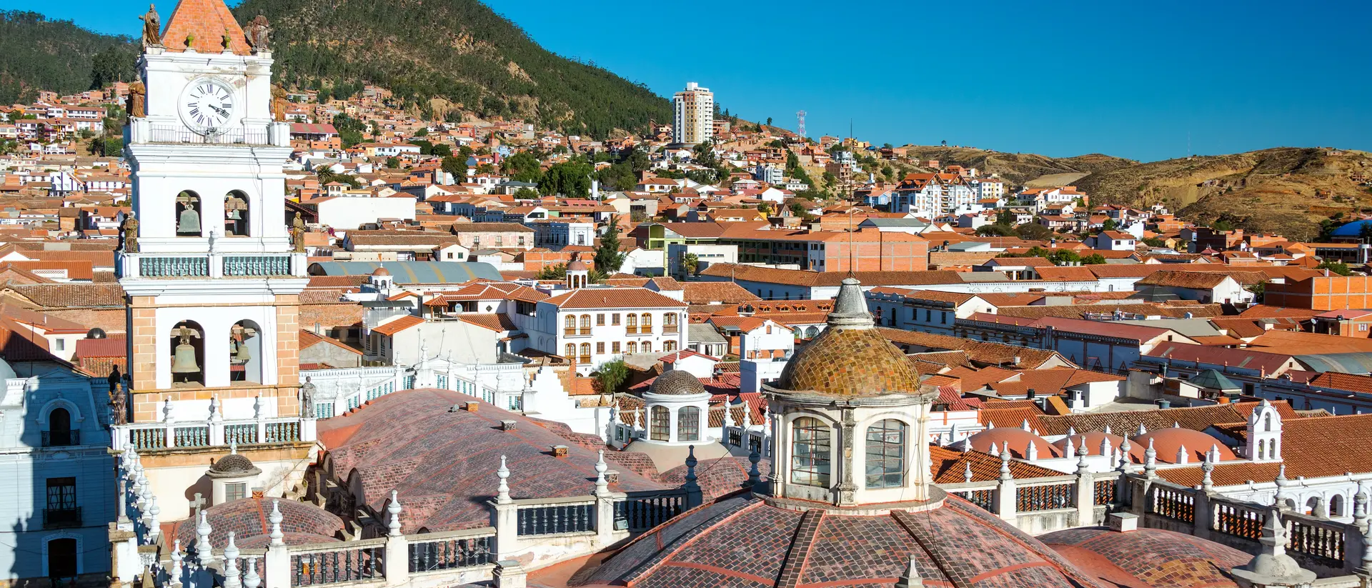 View of white colonial cathedral clocktower and red roofs in Sucre, Bolivia known as the White City