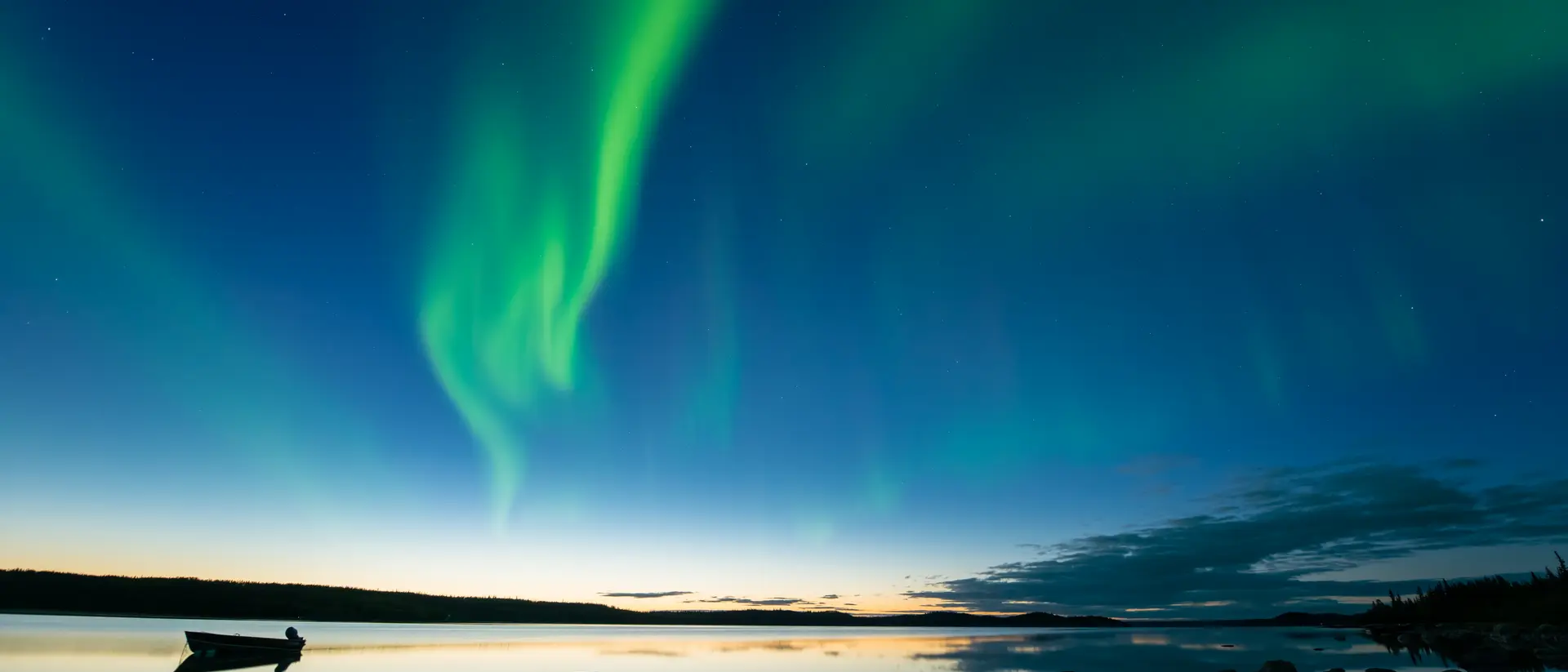 Yellowknife, Canada Bands of curvy aurora borealis appear over a northern rocky lake right after sunset.