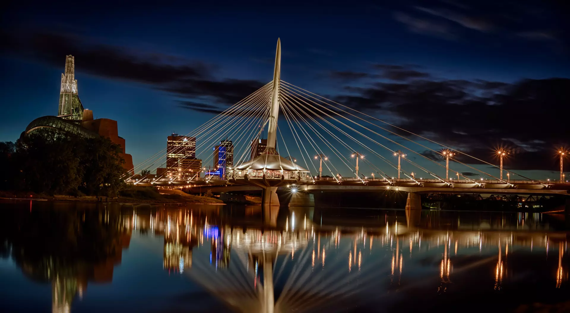 Red River, Winnipeg, Canada Reflection of the city skyline and the Esplanade Riel Bridge over the Red River at the blue hour