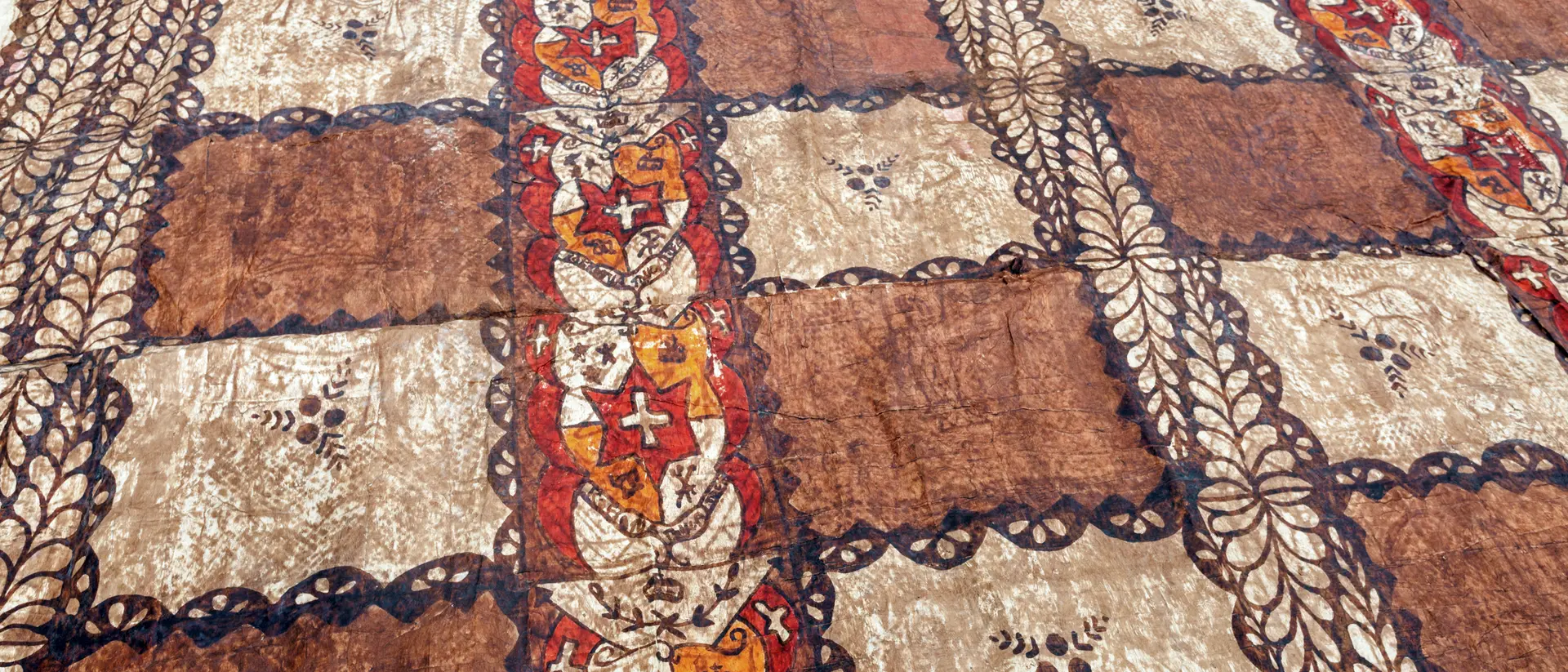 Patterned fabric with alternating brown and beige squares, featuring stylized floral designs and intricate borders.