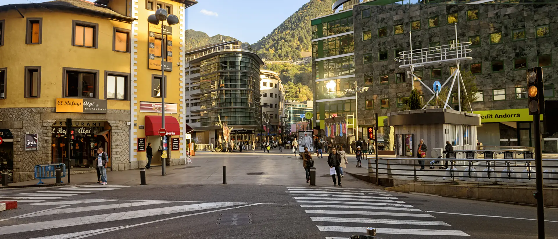 A city square with a mix of modern and traditional buildings, pedestrians crossing a striped crosswalk under a clear sky.