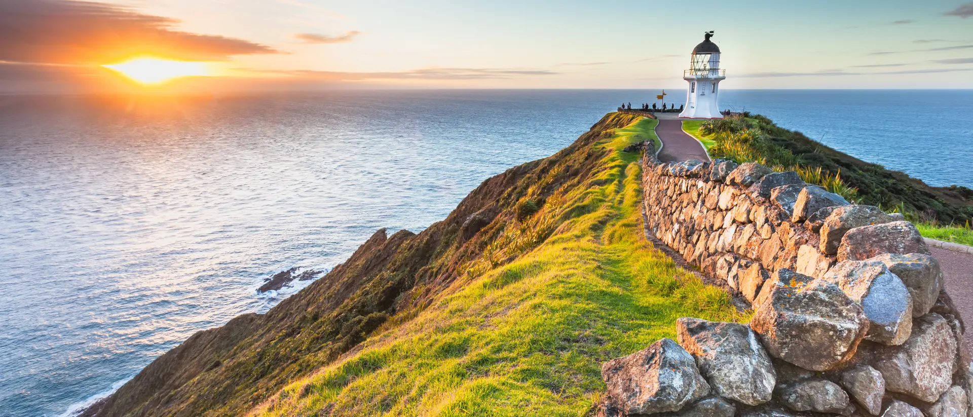Lighthouse at edge of cliff at sunset