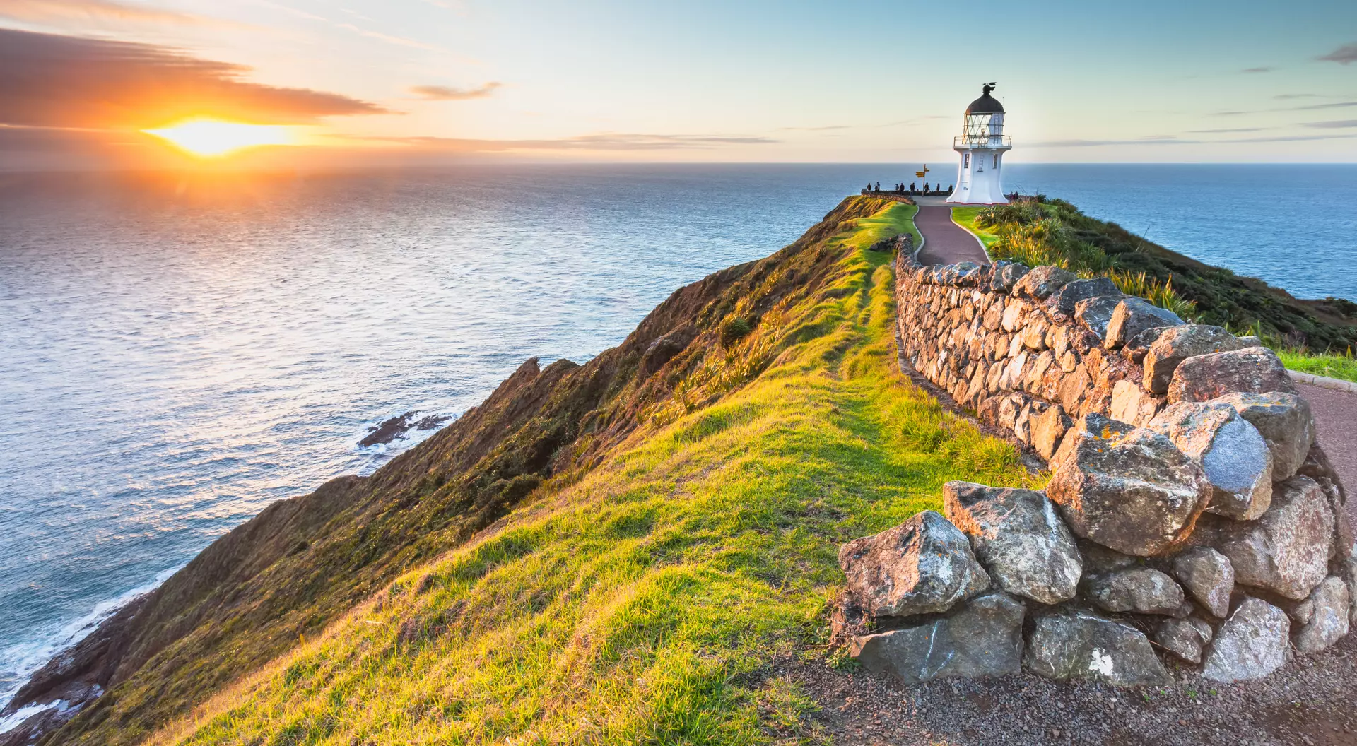 Lighthouse at edge of cliff at sunset