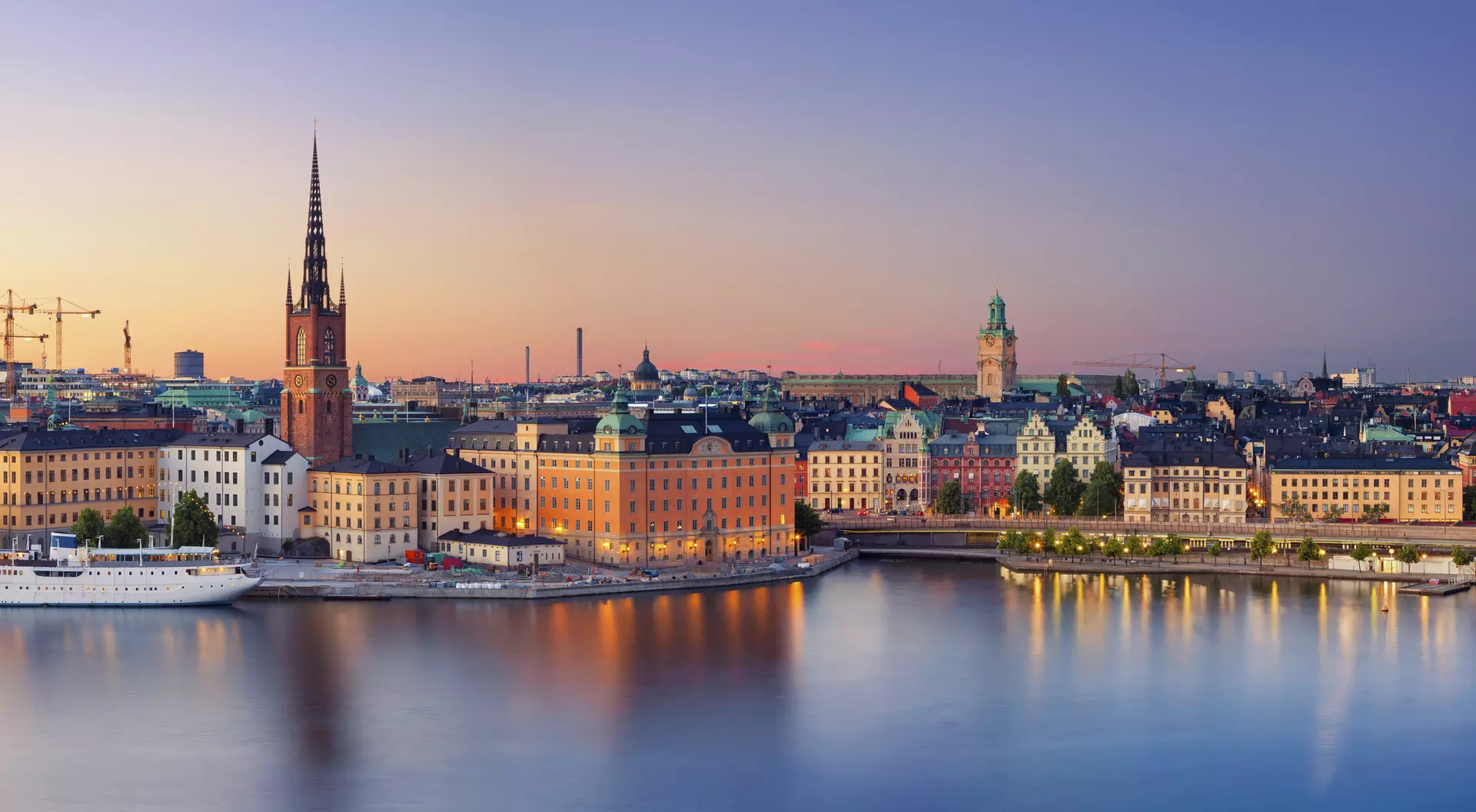 Panoramic view of Stockholm's waterfront at sunset, showcasing historic buildings and calm waters.