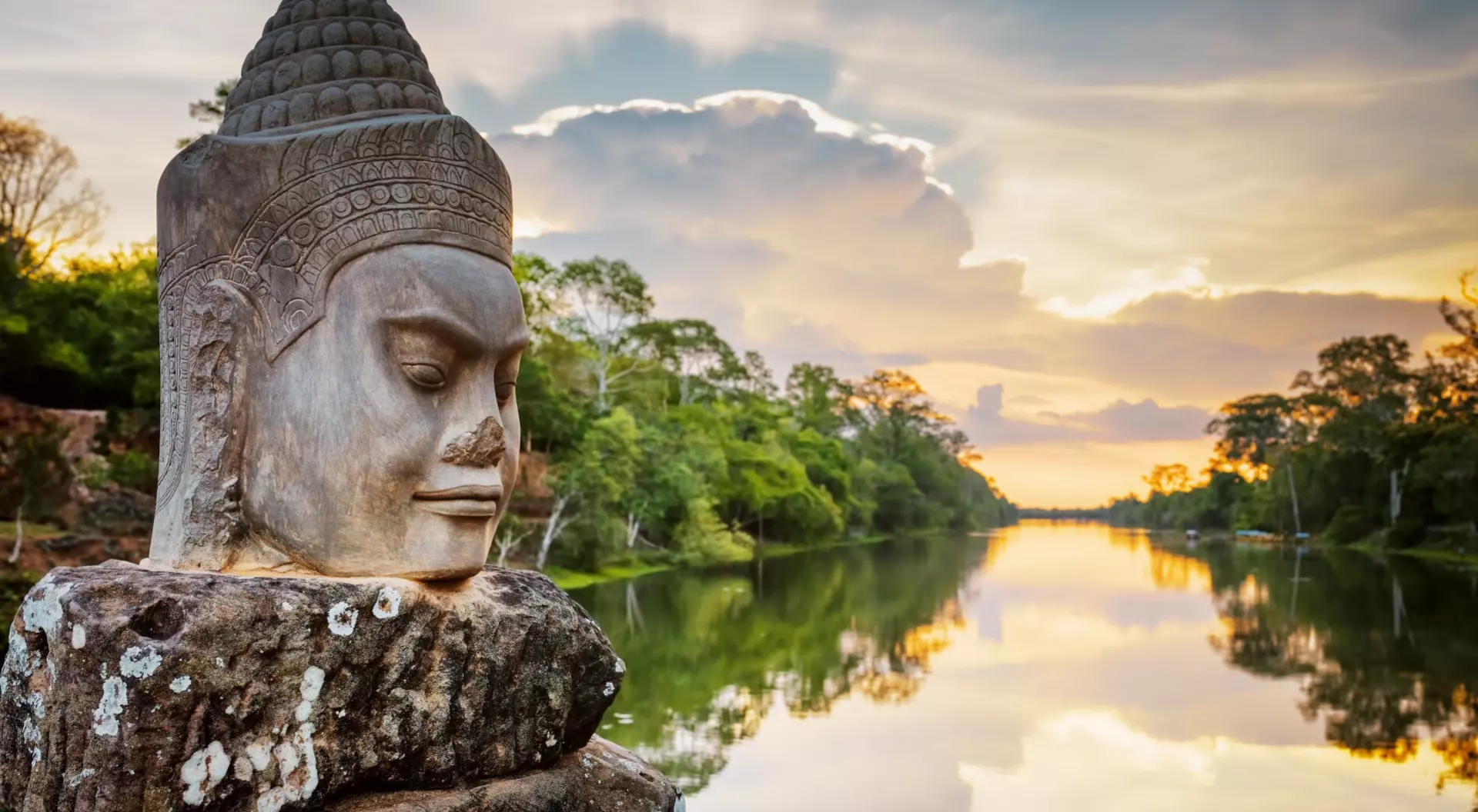 Stone face Asura over moat on causeway near South Gate of Angkor Thom in Siem Reap, Cambodia