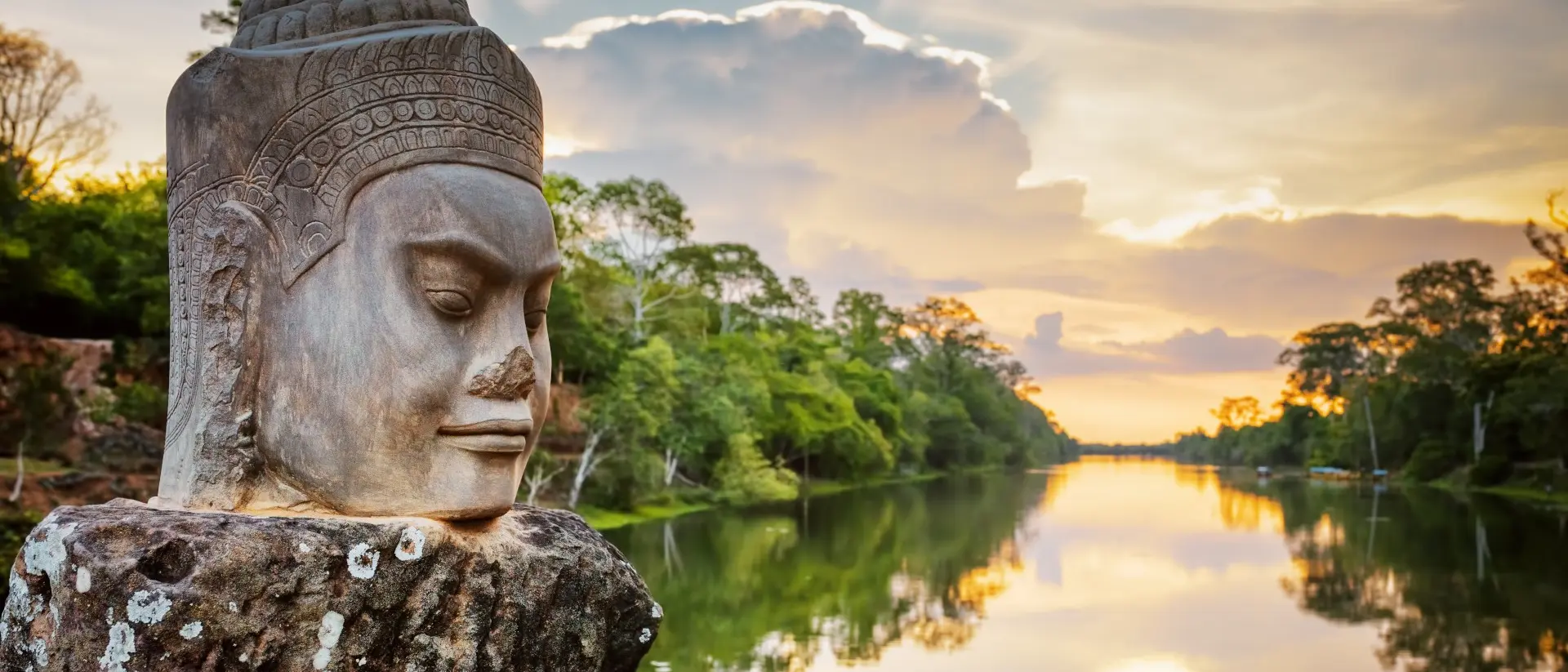 Stone face Asura over moat on causeway near South Gate of Angkor Thom in Siem Reap, Cambodia