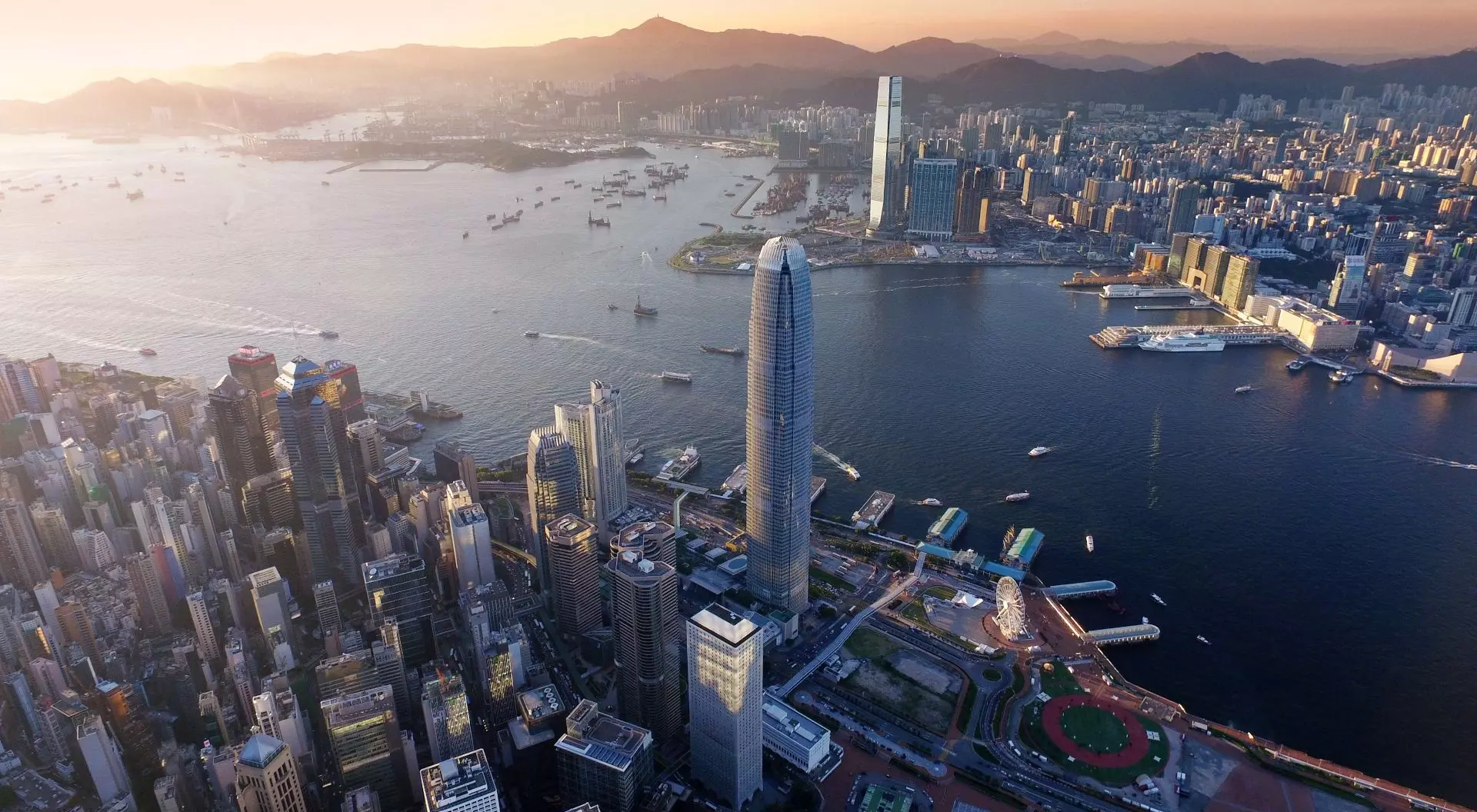 Dramatic skyline of Hong Kong Island and busy ships navigates across the Victoria Harbour during beautiful sunset