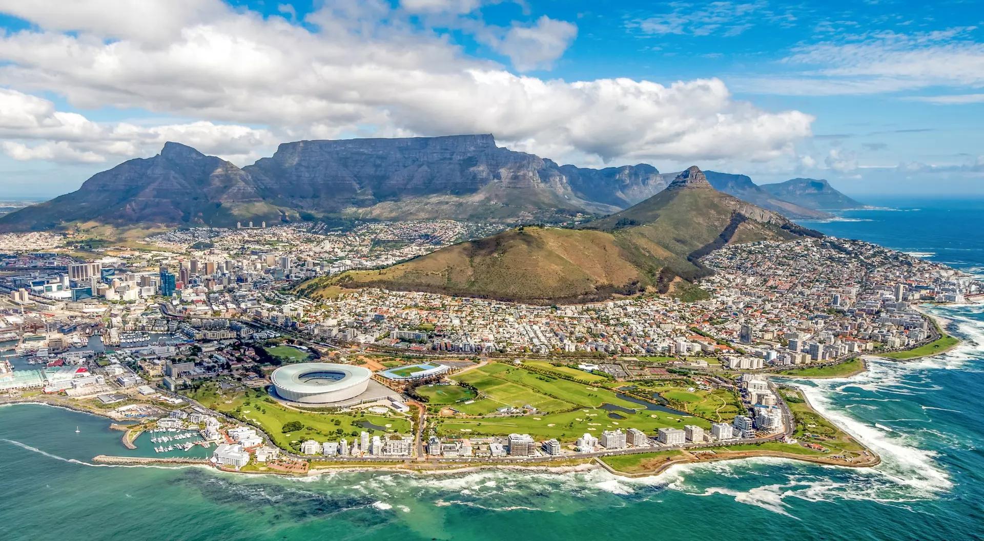 Aerial view of Cape Town, featuring the stadium, coastline, and iconic Table Mountain in the background.