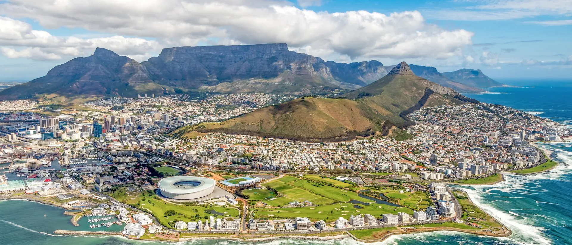 Aerial view of Cape Town, featuring the stadium, coastline, and iconic Table Mountain in the background.
