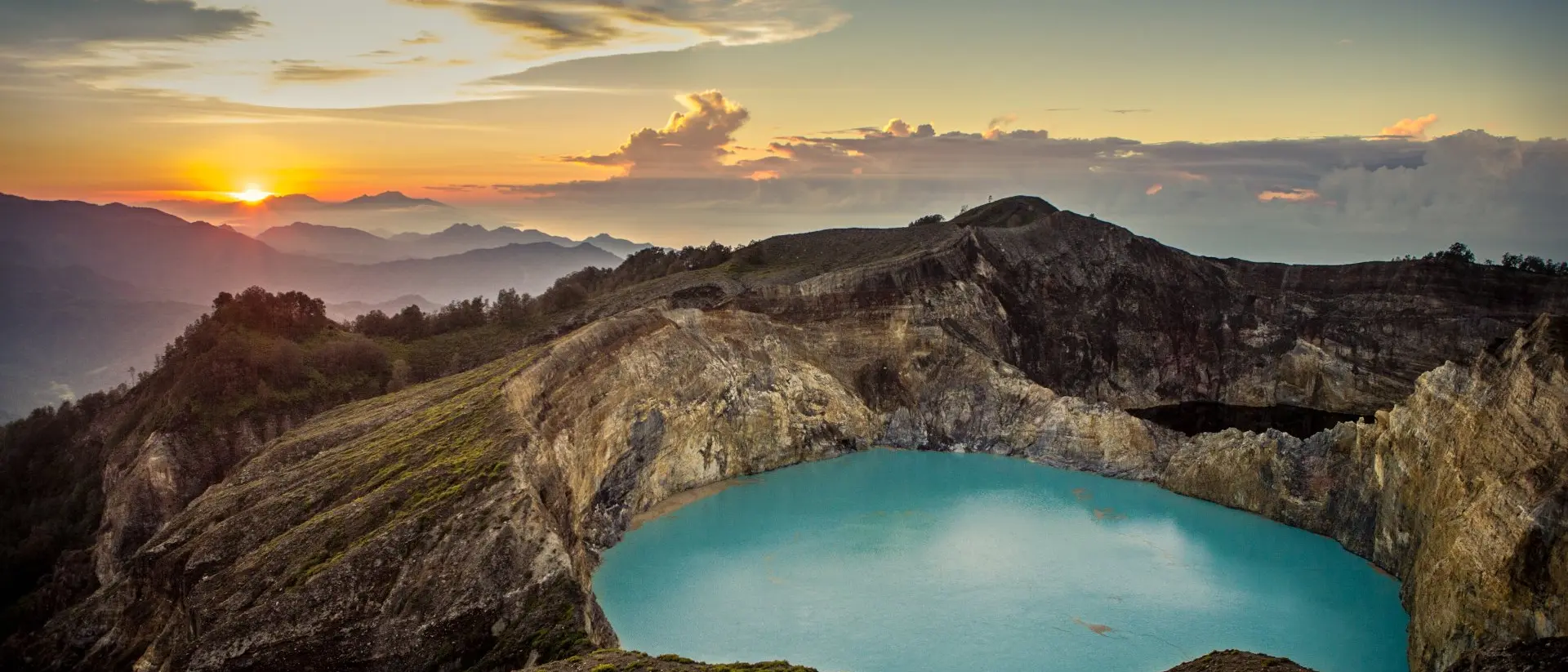 Kelimutu Volcano Sunrise on top of the Kelimutu volcano, featuring beautiful aqua colored crater lake at centre. Flores, Indonesia.
