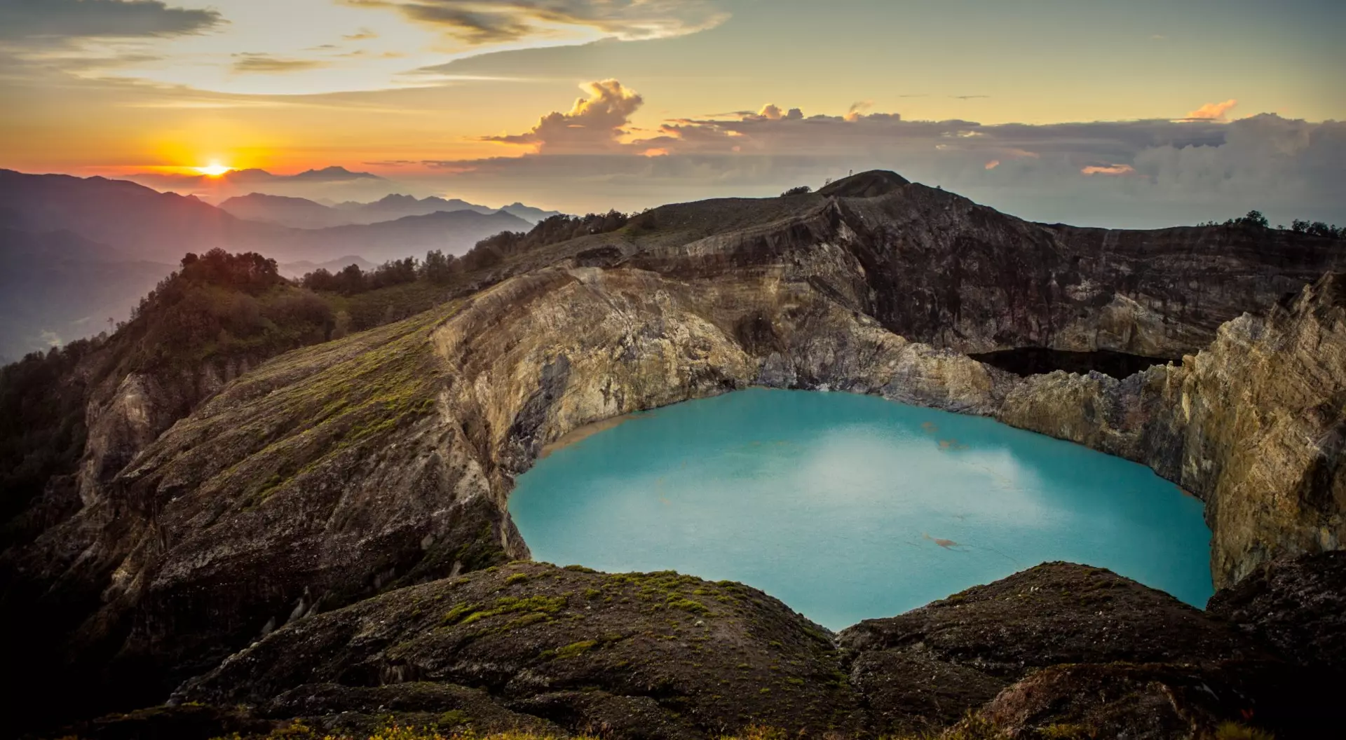 Sunrise on top of the Kelimutu volcano, featuring beautiful aqua colored crater lake at centre. Flores, Indonesia.