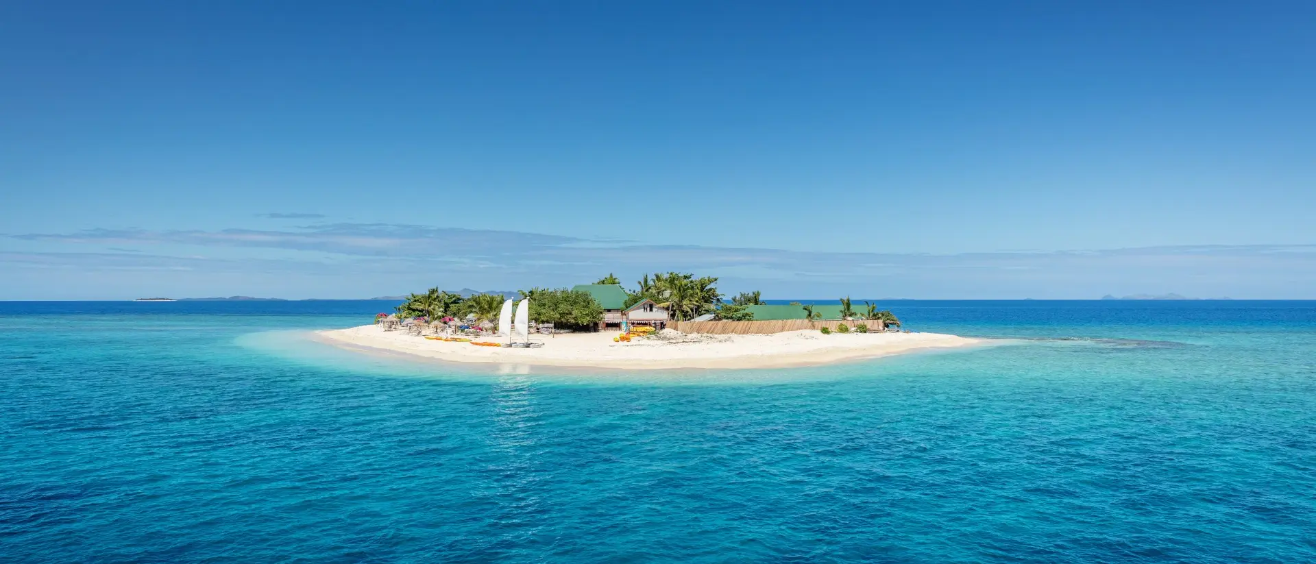 Mamanuca Islands Beautiful small island in the middle of the south pacific ocean with beach huts, lounge chairs, palm trees, surrounded with beautiful clear turquoise water.