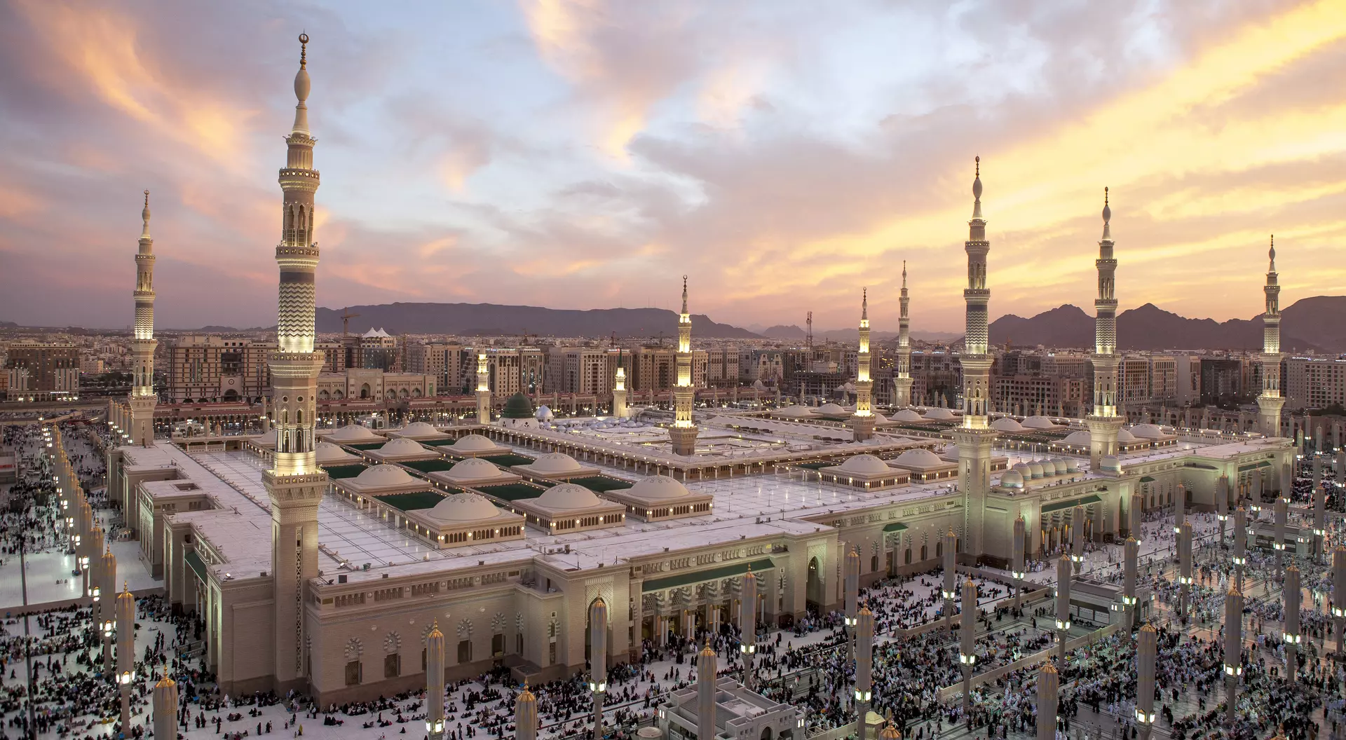 Masjid al-Nabawi Mosque in Medina, Saudi Arabia, featuring an iconic green dome and tall and slender minaret towers
