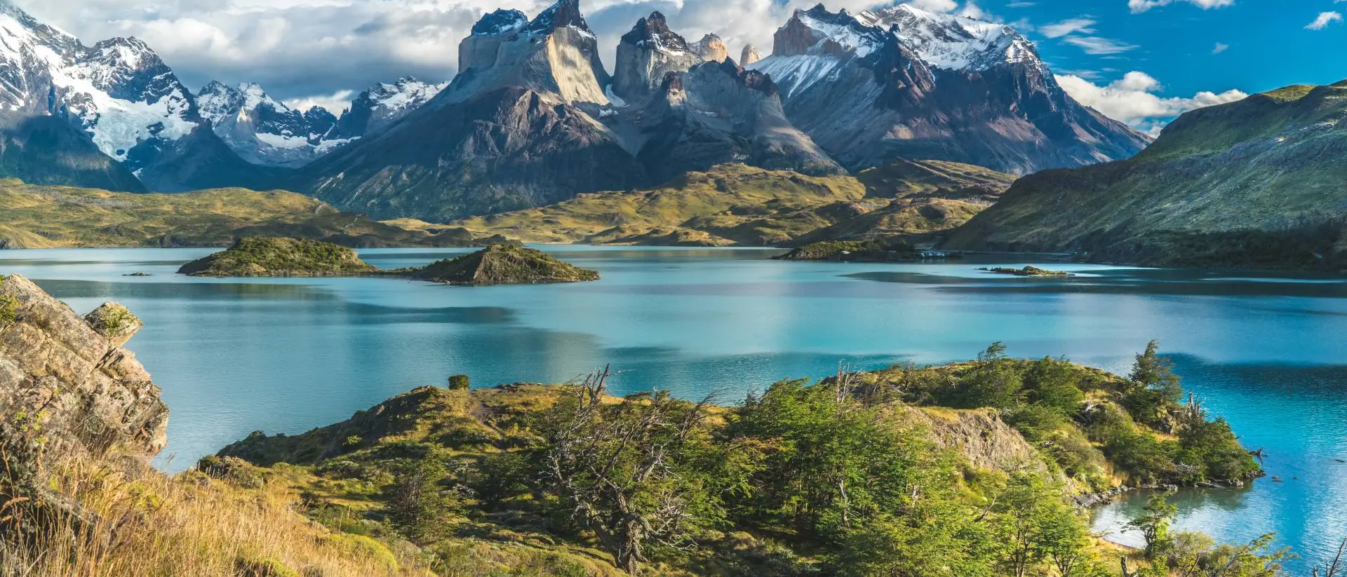 Blue lake on a snowy mountains background and cloudy sky