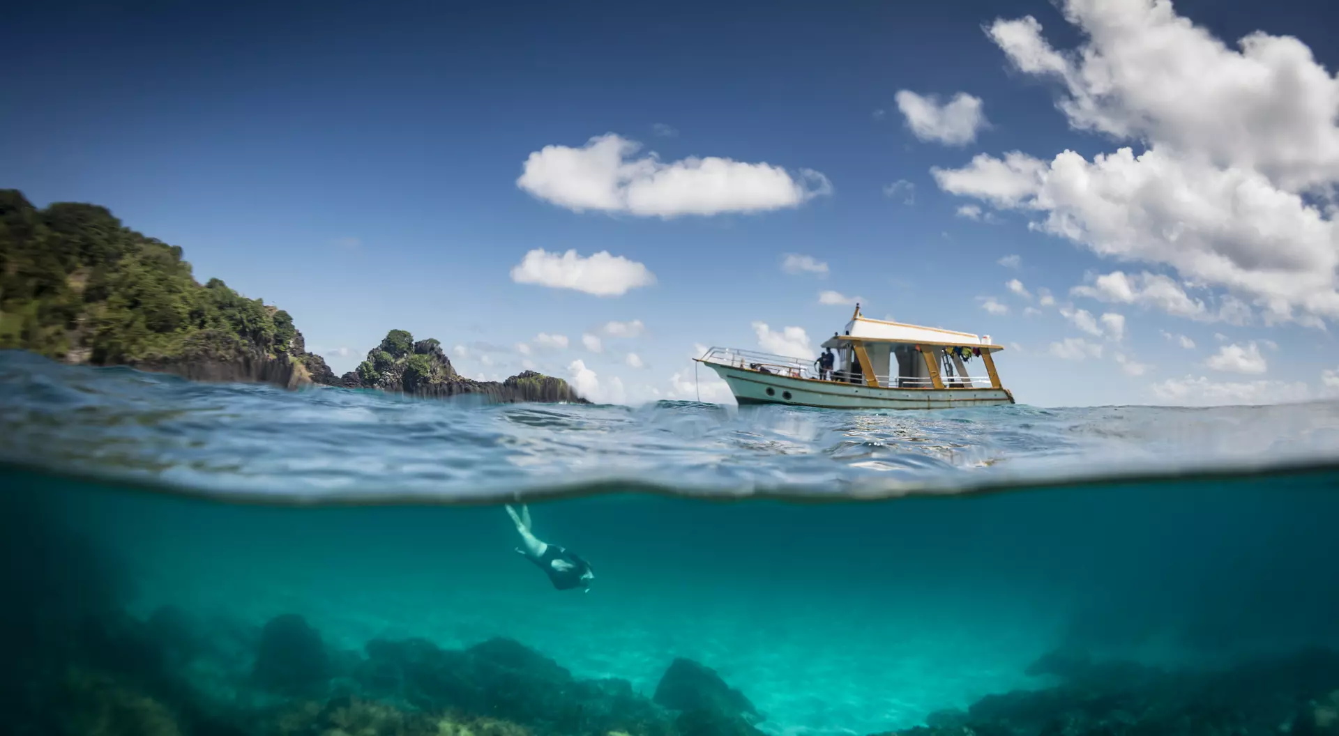 Fernando de Noronha View of a tour boat and a woman free diving at 'Sancho' beach in the archipelago of Fernando de Noronha
