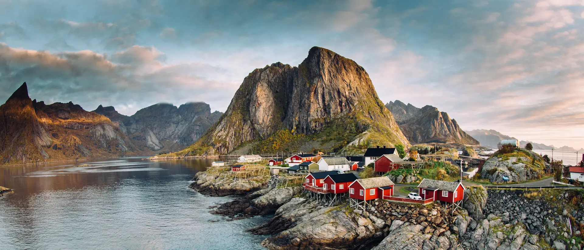 Dramatic sunset clouds moving over steep mountain peaks of Norwegian fishing village in the Lofoten Islands in Norway.