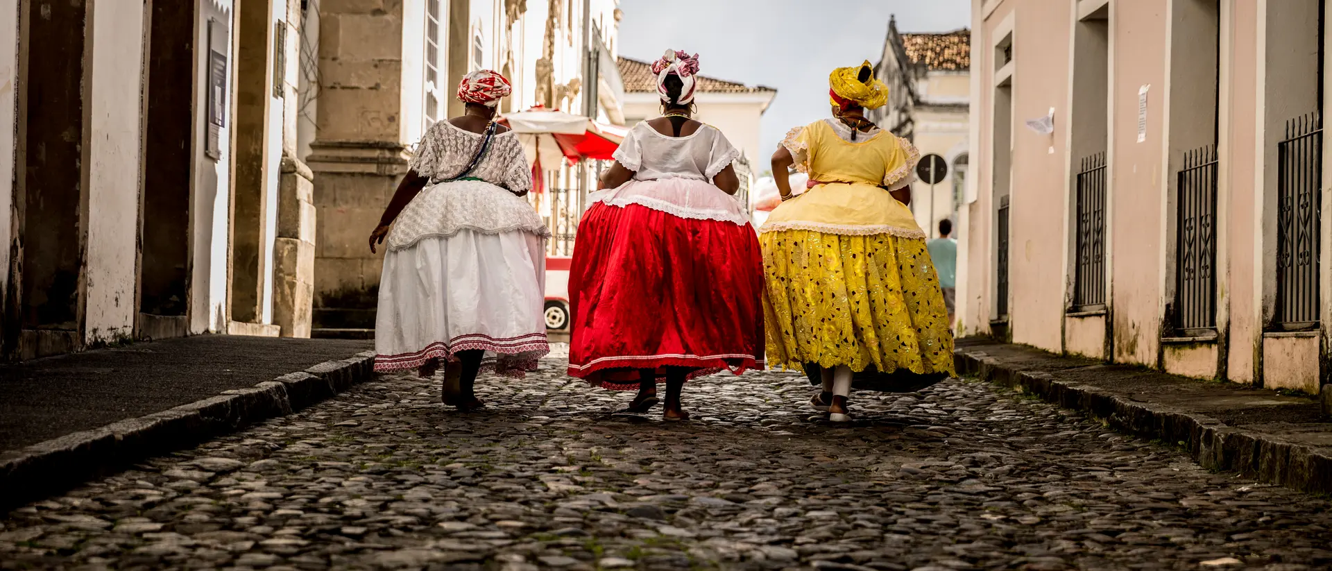 Group of "Baianas" walking in the famous Pelourinho cobblestone road in Salvador, Bahia, Brazil