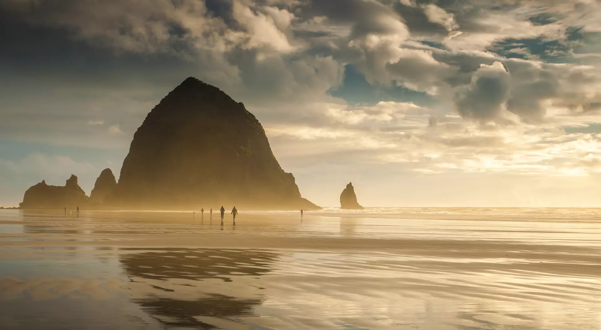 Ecola State Park Oregon's Cannon Beach at sunset and in between storms. People can be seen strolling on the beach.